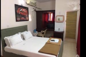 a bedroom with a large white bed and a table at Anandan Tourist Home in Varkala