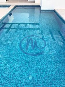 a blue swimming pool with a sign in the water at Casita de Moana in Puerto Peñasco