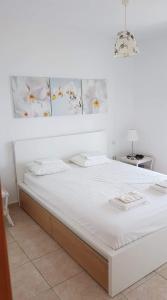 a bed with white sheets and flowers on the wall at PANORAMA HOUSE in Metókhion Konstamonítou
