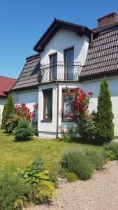 a white house with red flowers in the yard at Apartament STUDIO i Apartament ZADOMEK Spytkowice koło ZATORA in Spytkowice