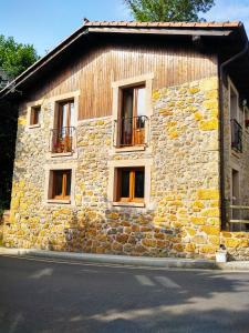 a stone building with three windows and a balcony at Casa de Aldea La Xunta in Cangas de Onís