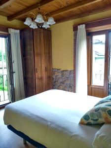 a bedroom with a large white bed and windows at Casa de Aldea La Xunta in Cangas de Onís