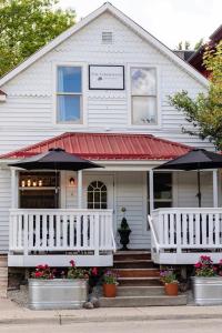 a white house with a porch and an umbrella at The Farmhouse Inn & Kitchen, 2 blocks from Downtown Whitefish, Montana in Whitefish