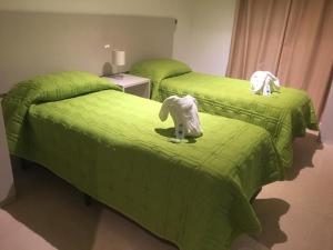 2 camas verdes con animales de peluche en una habitación en Lumminis Resort & Spa, en Santa Ana