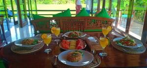a wooden table with plates of food and glasses of orange juice at Bali Harmony Villa in Ubud