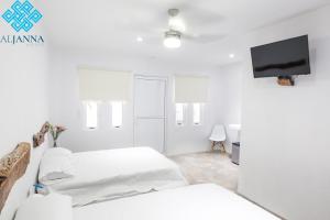 a white room with two beds and a flat screen tv at Aljanna House in Bacalar