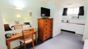 Habitación con escritorio y dormitorio con cama. en Tweed Heads Vegas Motel en Tweed Heads