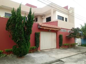 una casa con una pared roja y un garaje blanco en Pousada Nossa Casa en Aparecida