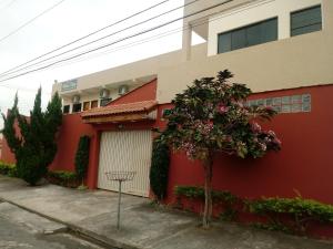 a red building with a tree in front of it at Pousada Nossa Casa in Aparecida