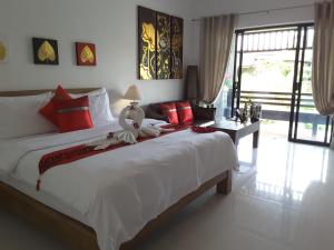 a bedroom with a large white bed with red pillows at Arthaya Villas - SHA Extra Plus in Ko Lanta