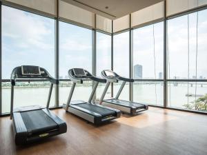 a gym with three cardio machines in a room with windows at Novotel Danang Premier Han River in Danang