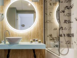 a bathroom with a sink and a mirror and a shower at Mercure Orléans Portes de Sologne in Ardon