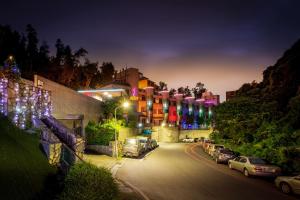 Una calle de la ciudad por la noche con coches aparcados en la calle en Only Love Motel en Xindian