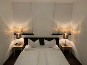 a bedroom with a bed with two lamps on two tables at Hotel Augsburg Langemarck in Augsburg