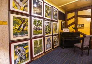 una habitación con una pared de cuadros y un piano en Cochrane Place Hotel, en Kurseong