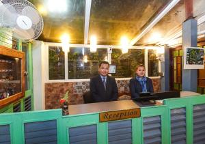 two people sitting at a counter in a restaurant at Cochrane Place Hotel in Kurseong