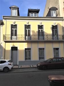 une voiture blanche garée devant un bâtiment jaune dans l'établissement Villa Tarbis Tarbes centre ville , appartements tout confort, à Tarbes
