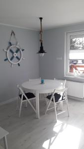 a white dining room with a white table and chairs at Apartament Nadmorski LUX1 in Sztutowo