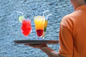 a man holding a tray with two drinks on it at Mui Tau Hotel Phan Ri Cua in Tuy Phong