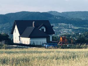 a white house with a black roof on a hill at Holiday home Limanowa in Limanowa
