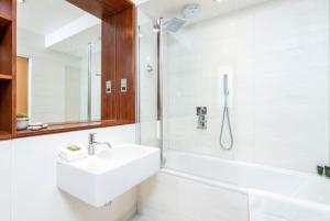 La salle de bains blanche est pourvue d'un lavabo et d'une douche. dans l'établissement Haggerston Studios, à Londres