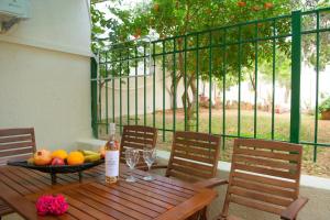 a wooden table with a bowl of fruit and wine glasses at Ammoudara Beach Hotel Apartments in Agios Nikolaos