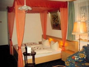 sypialnia z łóżkiem z baldachimem i pomarańczowymi zasłonami w obiekcie Hotel Gasthof Turm w mieście Grünhaid