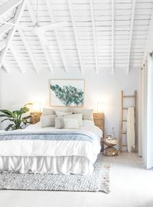 a white bedroom with a large bed with white walls at Elysian Luxury Eco Island Retreat in Long Island