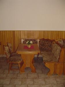 Pension Baron في فرتشلابي: طاولة خشبية عليها كرسيين وطاولة عليها ورد