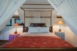 a bedroom with a canopy bed with two lamps at Pondok Pisang Candidasa in Candidasa