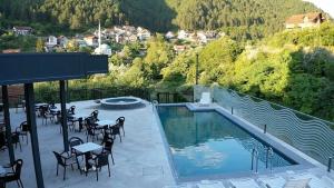 a swimming pool with tables and chairs on a balcony at Hotel Novalić Konjic in Konjic