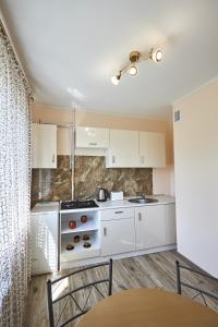 a kitchen with white cabinets and a stove top oven at Babylon Apartments On Kievskaya Street in Rivne