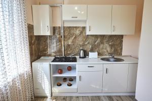 a small kitchen with white cabinets and a sink at Babylon Apartments On Kievskaya Street in Rivne