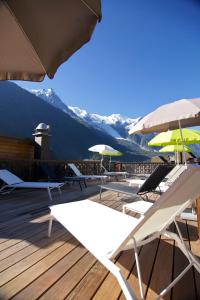 eine Gruppe von Liegestühlen und Sonnenschirmen auf einer Terrasse in der Unterkunft Park Hotel Suisse & Spa in Chamonix-Mont-Blanc