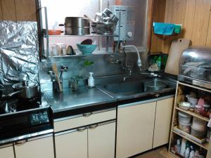 eine Küche mit Spüle und Mikrowelle in der Unterkunft 昭和の宿 汐凪 shionagi in Towa