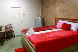 a bedroom with a red bed with two stuffed hearts at Ban Khun Rin Homestay in Amphawa