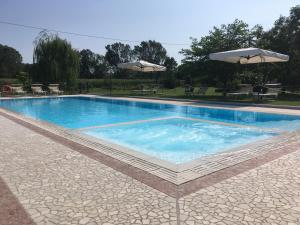 una grande piscina con due ombrelloni sopra di Agriturismo La Cascinetta a Pieve di Cento