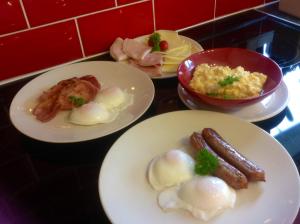 tres platos de comida en un mostrador con huevos y tocino en Dunroamin Bed and Breakfast, en Aviemore