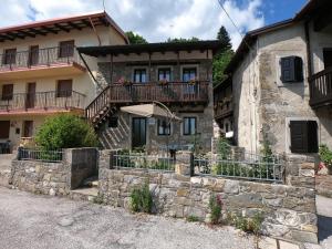 Casa de piedra antigua con balcón en una calle en Agriturismo Bozica en Montemaggiore