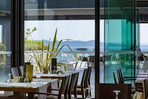 a restaurant with tables and chairs and a large window at Hotel Pinija in Petrcane