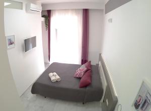 una camera da letto con un letto con due cuscini e una finestra di Be Inn a Salerno