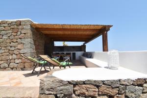 - un patio aux murs de pierre avec une table et des chaises dans l'établissement DAMMUSI IL CARRUBO, à Pantelleria