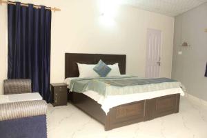a bedroom with a bed with blue curtains and a chair at Comfort Point Bed & Breakfast in New Delhi