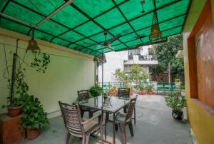 a patio with a table and chairs and a green canopy at Comfort Point Bed & Breakfast in New Delhi