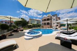 a swimming pool with two lounge chairs and an umbrella at Apartments Tony in Biograd na Moru