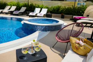 een zwembad met een tafel en stoelen met wijnglazen bij Apartments Tony in Biograd na Moru