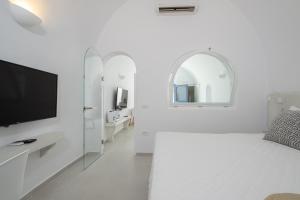 a white room with a bed and a tv at Santo Castello in Akrotiri