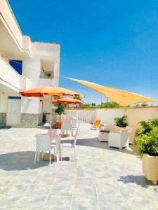 een patio met tafels, stoelen en parasols bij Residence Le Palme in Marina di Mancaversa