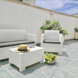 a patio with two chairs and a hat on a table at Residence Le Palme in Marina di Mancaversa