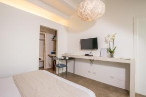 a bedroom with a bed, desk and television at Hotel Intorno Al Fico in Fiumicino